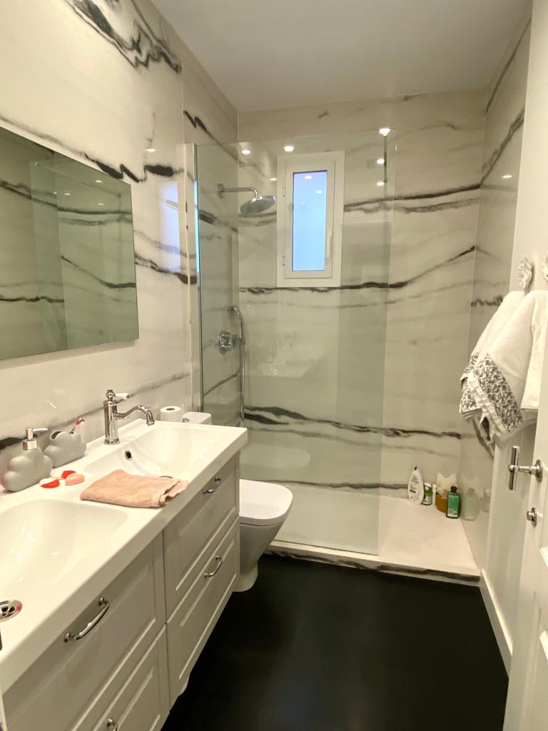Lavabo con plato de ducha y revestimientos en Neolith blanco con vetas negras