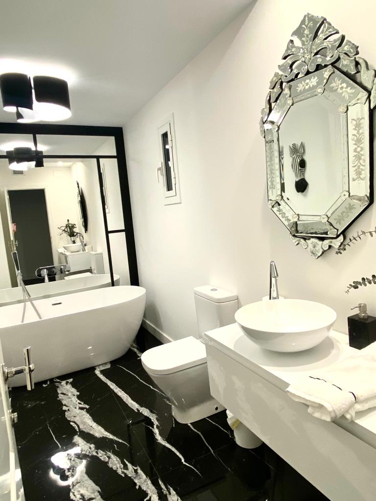 Lavabo con bañera de diseño y suelos de mármol en piso reformado de Barcelona