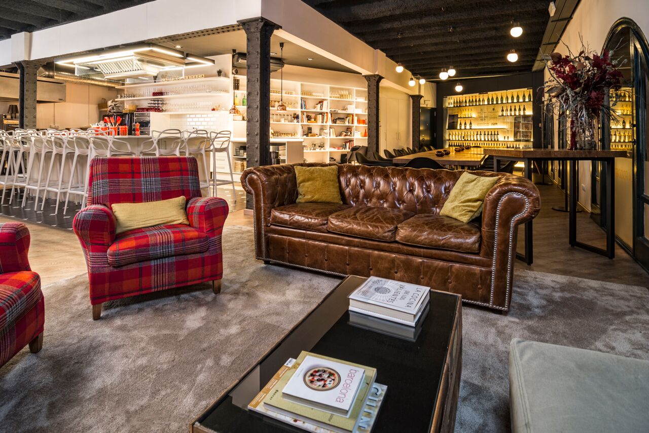 Zona de relax en La Foodieteca con sillón Chester y butacas rojas de diseño